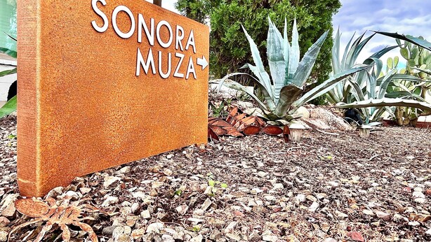 A sign for Sonora Muza with a textured orange background and white lettering.