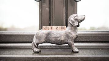 Una figurita de perro de metal con bloques de madera que deletrean 'SUN 12 DEC' sobre un alféizar.