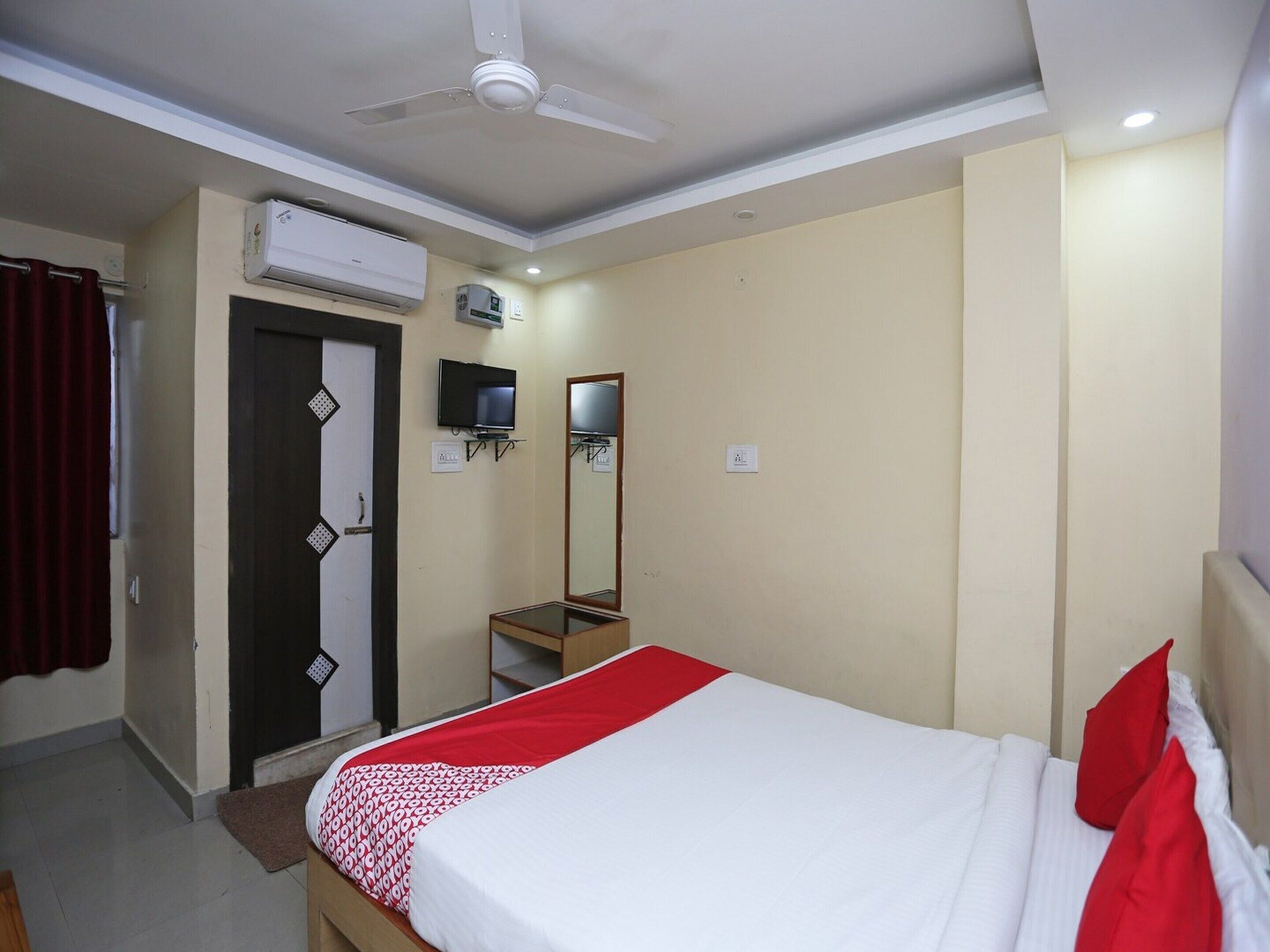 Ein Hotelzimmer mit Bett, Fernseher, Klimaanlage und Deckenventilator.