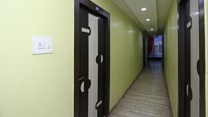 En hall med dörrar som är numrerade, en ljusströmbrytare och en utsikt över omgivningen i slutet av hallen.