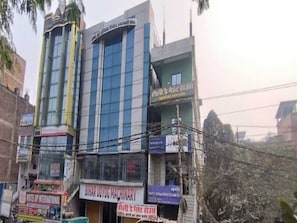 Un immeuble à plusieurs étages abritant divers commerces au rez-de-chaussée, notamment un hôtel et un atelier de mécanique.