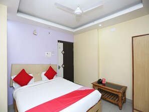 Une chambre à coucher avec un lit, une table de chevet, un ventilateur de plafond et une porte.