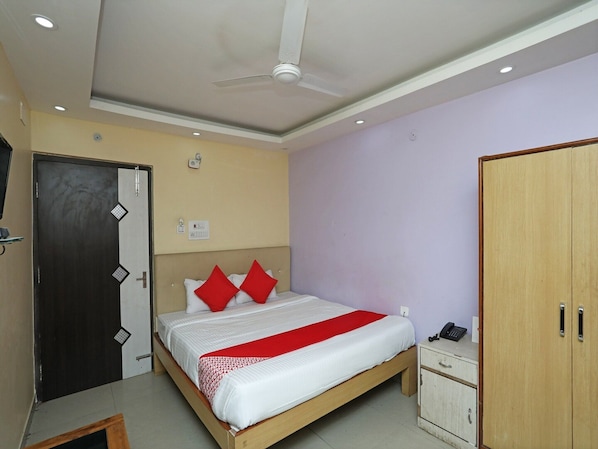 Une chambre à coucher comprenant un lit, une armoire, une table de chevet et un ventilateur de plafond.