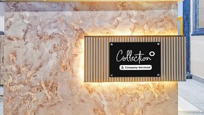 Bancada de recepção com superfície semelhante a mármore e uma placa com a inscrição 'Collection Company-Serviced'.