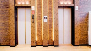 A modern elevator with vertical wooden panels and illuminated edges, a phone, and emergency buttons. - Townhouse Oak Ulwe (Panvel)