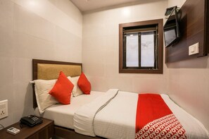 A hotel room with a bed, a bedside table with a telephone, a window, and a wall-mounted television. - Townhouse Oak Ulwe (Panvel)