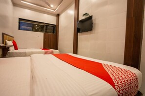 A hotel room with two beds, a TV mounted on the wall, and a window with a view. - Townhouse Oak Ulwe (Panvel)