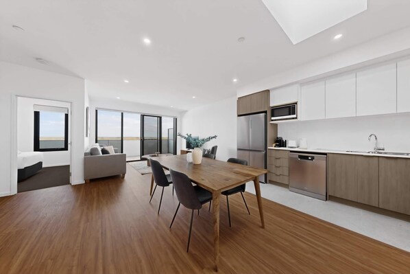 A modern kitchen with a dining area, a large window, and a view.