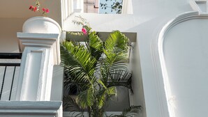 A white building with a balcony, a potted plant, and a window. - ELIVAAS Fernweh 4 BHK with Pool (Assagao)