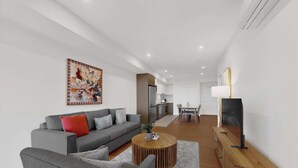 A modern living room with a grey sofa, a coffee table, and a TV on a wooden stand.