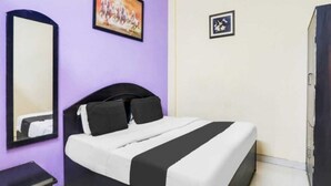 Een hotelkamer met een bed, een spiegel, een schilderij aan de muur en een deur.