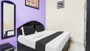 Een kamer met een bed, een spiegel en twee ingelijste foto's aan de muur.