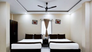 A bedroom with two beds, a ceiling fan, a wardrobe, and two butterfly paintings on the wall.