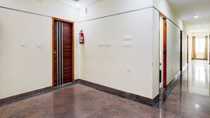 A hallway with a fire extinguisher, a wooden door, and a light switch on the wall.