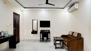 A living room with a ceiling fan, a flat-screen TV, a sofa, a coffee table, and a small desk.