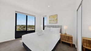A bedroom with a large bed, a nightstand, a lamp, and a painting.