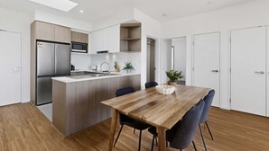 A modern kitchen with a central island, a dining area with a wooden table and chairs, and a small kitchenette.