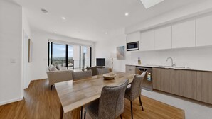 A modern kitchen with a dining area, large windows, and a view.