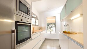 Een moderne keuken met roestvrijstalen apparatuur, een raam met uitzicht en een aanrecht met kristalglas.