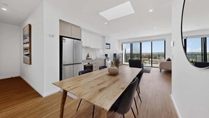 A modern kitchen with a dining area, a large window with a view, and a minimalist design.