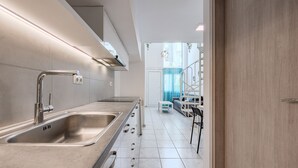 Cozinha moderna com eletrodomésticos de aço inoxidável, pia embutida e bancada iluminada.