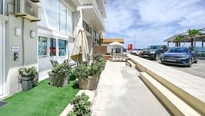 Hotel com área externa para sentar, aparelhos de ar condicionado e carros estacionados.