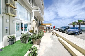 A hotel with outdoor seating, air conditioning units, and parked cars. - Kalimera Beach Apartment 2 – Town Experience : (Rethymno)