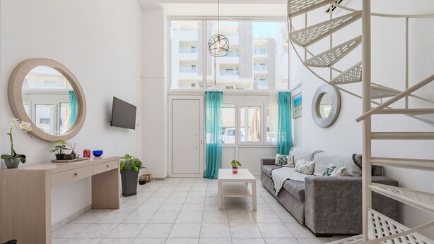 Un salon moderne avec un canapé, une table basse, un téléviseur et un escalier.