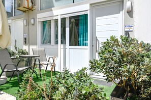 A hotel room with a sliding door, a small table with chairs, and a potted plant. - Kalimera Beach Apartment 1 – Town Experience (Rethymno)