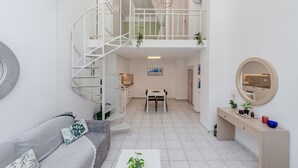 Un intérieur moderne avec un escalier en colimaçon, un coin repas et un espace de vie comprenant un canapé et une table basse.