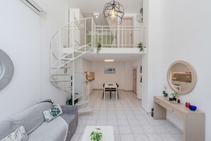 Un intérieur moderne avec un escalier en colimaçon, un coin repas et un espace de vie comprenant un canapé et une table basse.
