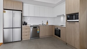 Eine moderne Küche mit weißen Schränken, einem eingebauten Geschirrspüler, einer Mikrowelle und einem Edelstahlkühlschrank.