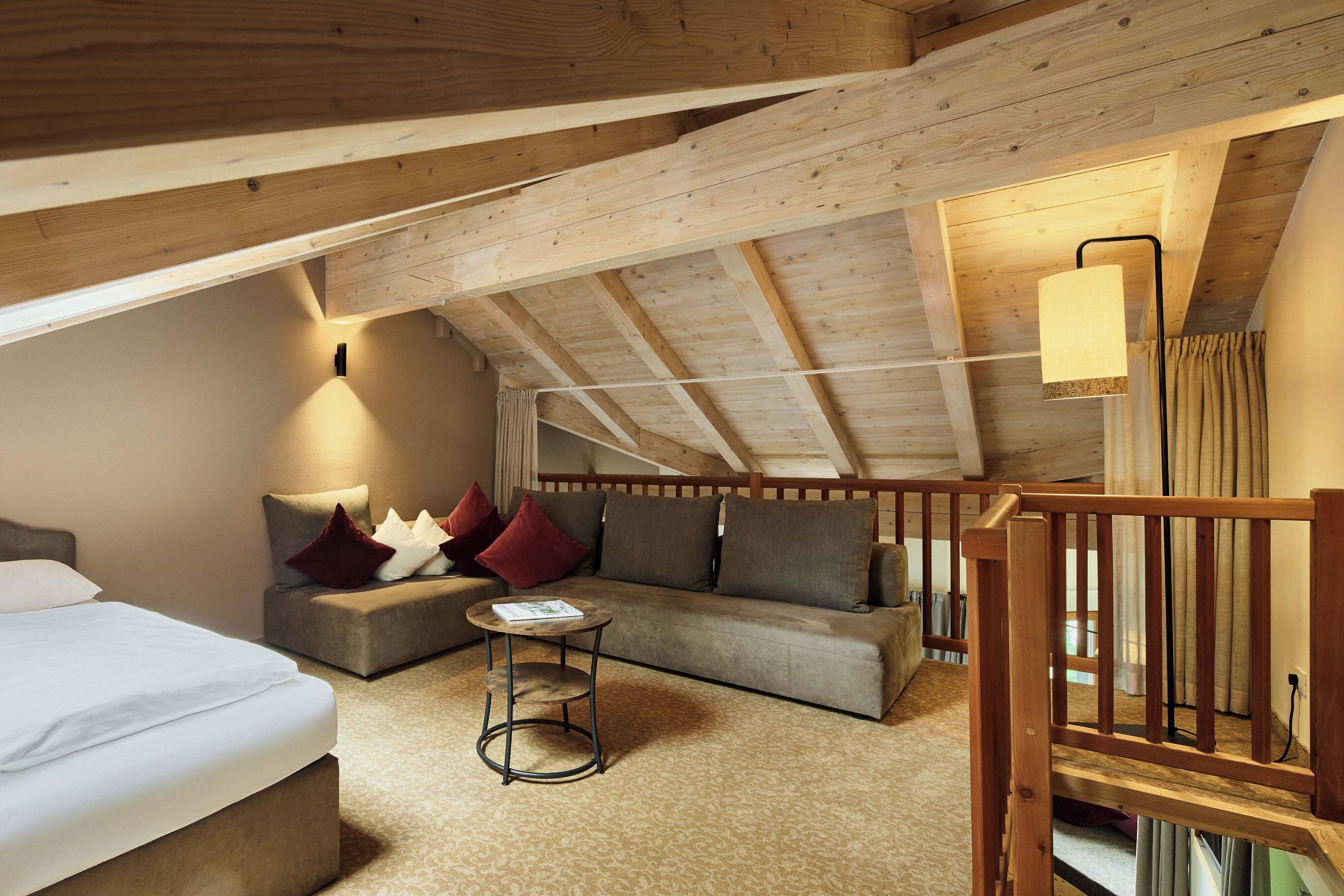 Une chambre à coucher confortable, aménagée en style « loft », avec un plafond haut, un canapé, une petite table ronde et un lit.