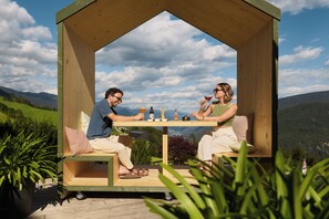 A wooden gazebo with a table and chairs, set against a mountainous backdrop. - Hotel AUI (Rio di Pusteria)