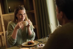 A person sitting at a table with a plate of food, a glass of water, and a cup. - Hotel AUI (Rio di Pusteria)