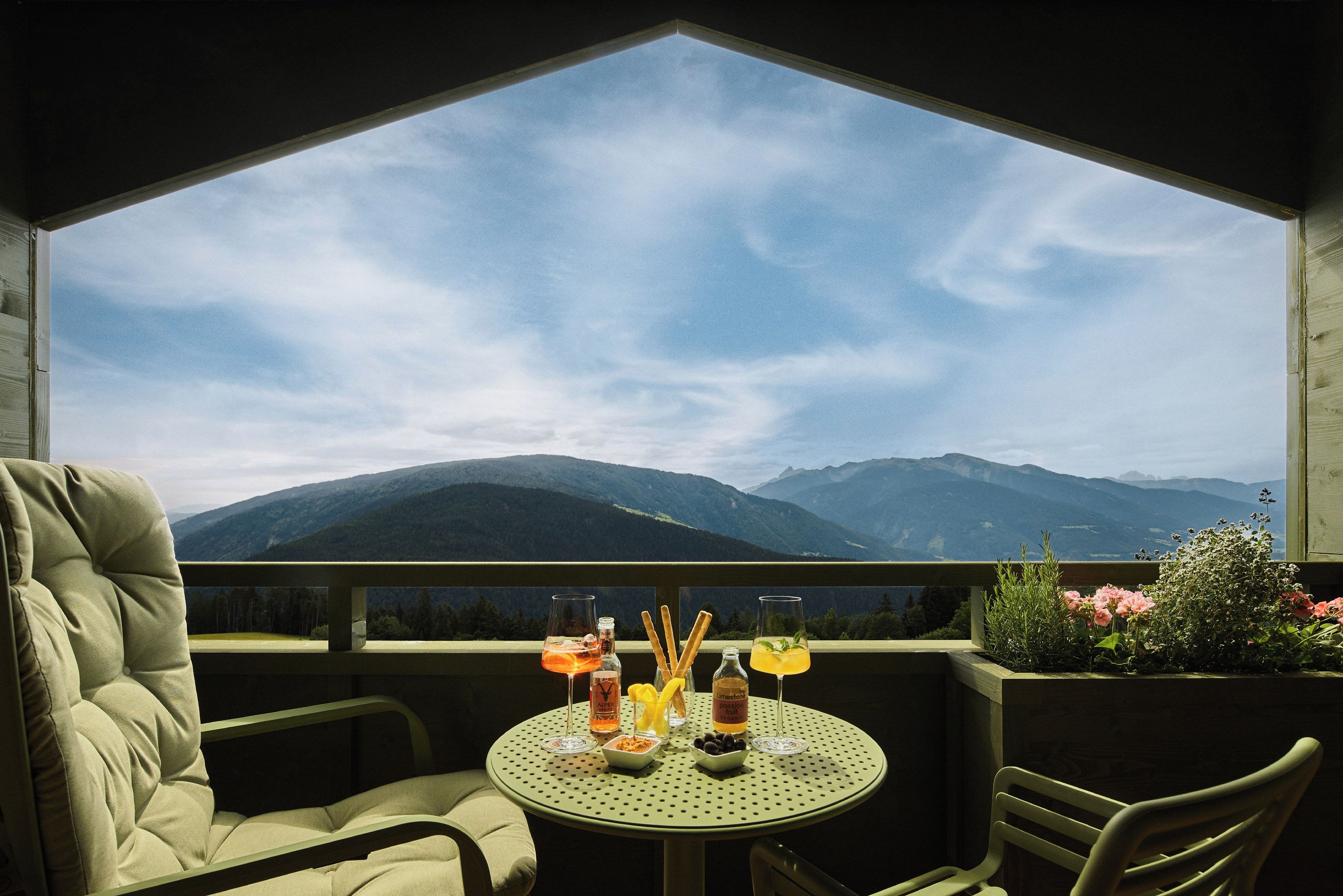 Un balcon avec une table dressée pour deux personnes, offrant une vue sur un paysage montagneux.