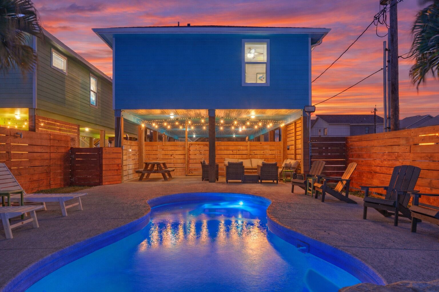 A backyard with a swimming pool, wooden deck, and outdoor seating.