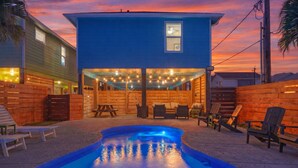 A backyard with a swimming pool, wooden deck, and outdoor seating. - Private Pool + Lounge + Mins to Shore & Dining | Beach House | Tickle My Fansea (Port Aransas)
