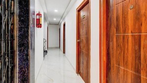 A hallway with wooden doors, a fire extinguisher, and a marble floor. - Collection O Nagaram Main Road Hyderabad (Hyderabad)