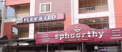 A multi-story building with a storefront for 'Sphoorthy' offering vegetarian cuisine.