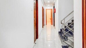 A hotel hallway with a marble floor, wooden doors, and a staircase with metal railings. - Collection O Nagaram Main Road Hyderabad (Hyderabad)