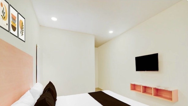 A hotel room with a bed, a TV mounted on the wall, and a shelf with storage. - Collection O Nagaram Main Road Hyderabad (Hyderabad)
