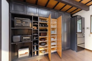 Una cocina con electrodomésticos integrados, estantes abiertos con vajilla y un refrigerador.