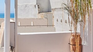 A terrace with a table set for dining, a potted plant, and a view of the sea. - Penthouse C diz Centro by Livework (Cádiz)