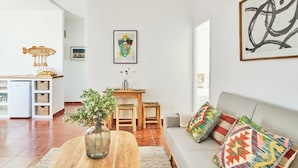 A modern living room with a sofa, a dining table, and a kitchen area in the background. - Penthouse C diz Centro by Livework (Cádiz)