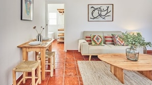 A living room with a sofa, a coffee table, a dining table with chairs, and a kitchen area in the background. - Penthouse C diz Centro by Livework (Cádiz)