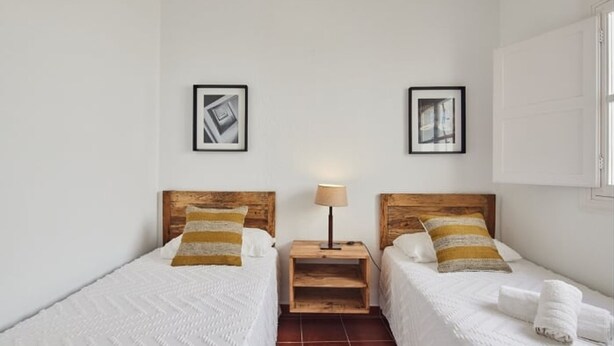 A hotel room with two beds, a nightstand, and two framed pictures on the wall. - Penthouse C diz Centro by Livework (Cádiz)