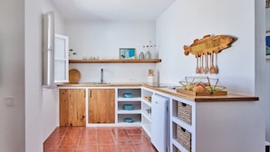 A compact kitchen with wooden cabinets, a white refrigerator, and a wooden countertop with a fruit bowl. - Penthouse C diz Centro by Livework (Cádiz)