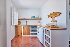 A compact kitchen with wooden cabinets, a white refrigerator, and a wooden countertop with a fruit bowl. - Penthouse C diz Centro by Livework (Cádiz)