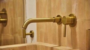 Ein Badezimmer mit einem goldfarbenen Wasserhahn und einem Wandhandtuchhalter.